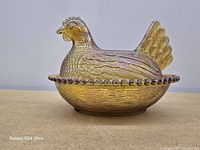 Side view of assembled hen-on-nest dish showing iridescent finish and bowl