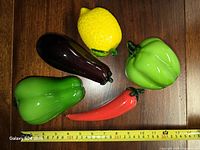 group shot of five glass vegetables with tape for scale