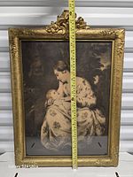 Front view showing lithograph and ornate gilt frame with tape measure for height