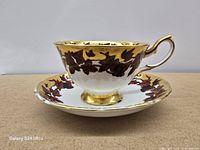 side view of tea cup on saucer showing leaf motif and gold trim