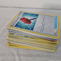 Stack of yellow-border Pokémon TCG cards, top card Crushing Hammer