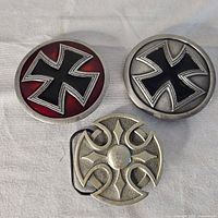 Front view of three metal belt buckles showing Iron Cross designs and stylized cross motif