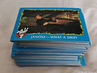 Stack of blue-border Ghostbusters II trading cards, top card Janosz—What a Drip!