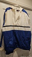 Front view of Nike white and blue windbreaker jacket hanging on hanger