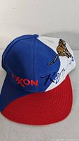 Front view showing red brim, white front panel, blue side panels, embroidered Exxon logo and tiger