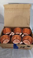 Six copper mugs inside original Smirnoff cardboard box