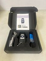 Open box showing keyfob camera, USB reader, cable, manual