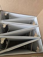 Open carton showing six white binders stacked