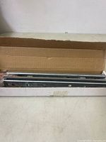 Open cardboard box showing metal rail sections inside