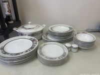 Entire dinnerware set displayed, showing tureen, stacks of plates, bowls, salt and pepper shakers