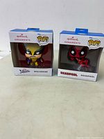Front view of both boxed Hallmark Pop! ornaments: Wolverine and Deadpool