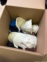 box containing stacked white caps with stickers and various coloured caps beneath