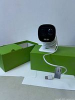 Camera on stand with coiled micro-USB cable and green Lorex box