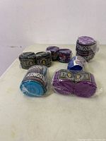 Overall view of six plastic-wrapped pairs of boxing hand wraps in assorted colours