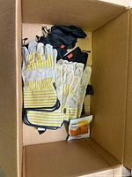 Box interior showing stacked leather gloves, drawstring pouches, and a packaged item