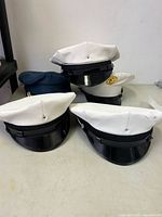 Group of five peaked caps, four white, one blue