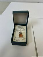 Necklace in green presentation box with information card visible