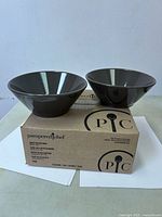 Two dark grey Pampered Chef bowls on top of original box