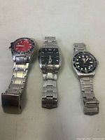 All three wristwatches laid out showing bracelets and dials