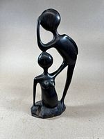 Front view of the hand-carved ebony wood sculpture of two connected abstract human figures on a base.