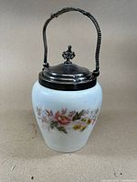 Full view of the antique milk glass container with floral design, metal lid and handle