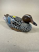 Front and side view of hand painted wooden duck decoy showing detailed feather pattern and painted colors