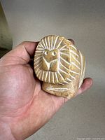 Front view of the carved stone lion held in hand showing the face and mane details.