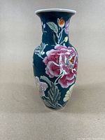 Front view of the famille rose vase showing detailed floral design on dark teal background