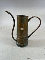 Side view of copper watering can showing cylindrical body, long curved spout, and handle.