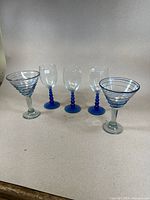 Group of five hand blown glasses: two martini glasses with blue spirals and three cobalt blue stemmed glasses.