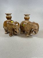 Pair of brown glazed porcelain elephant figurines with detailed carving and ornamental saddles