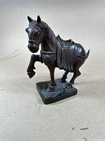 Full front-left angle of the intricately carved horse statue in dark brown showing mane and saddle details.