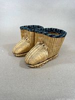 Pair of small Japanese straw shoes placed side by side on a plain surface showing overall woven straw construction and fabric trim.