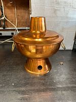 Front view of large copper Chinese soup holder hot pot showing rounded body, chimney, side handles, and base.