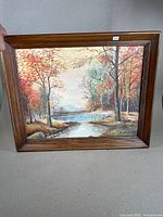 Full view of the framed oil painting showing the autumn river landscape and wooden frame.