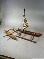 Pair of carved wooden boats including an outrigger and a sailboat with fabric sail shown together.