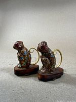 Pair of small Chinese cloisonné monkey figurines on wooden bases with brass tails