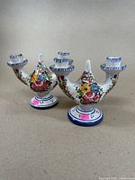 Two porcelain hand painted candle holders shown side by side with floral patterns and blue trim