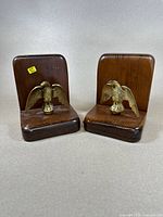 Pair of wooden book ends with brass eagle figurines mounted on them, shown front and side views.