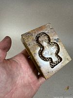 Top view of the small rectangular soapstone box held in hand, showing carved floral pietra dura inlay on lid.