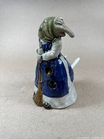 Porcelain Baba Yaga pen holder, side view showing broom and holes in apron for pens.