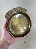 Top-down view showing the round brass container with the embossed 'SMALL CHANGE' text along the rim and patina spots inside the bowl.