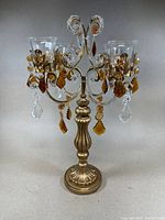 Front view of candelabra, showing overall design, metal base, and hanging amber and clear crystal pendants