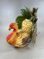 View of the full side profile of the vintage decorative turkey showing straw head, wooden carved feathers, and green straw tail.