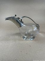 Side view showing full glass bird-shaped body with metal handle, spout and base