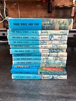 Stacked view of the 10 volumes of The Bible Story showing titles and author Maxwell on spine