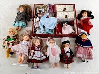 Eight dolls, open trunk and loose clothing displayed