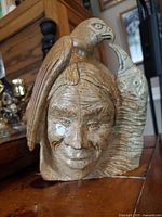 Front view of signed stone sculpture with face, bird, fish