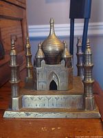 Front angled view showing brass Taj Mahal replica with minarets and central dome