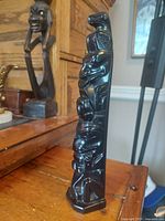 Front angled view of the polished black argillite Tahnoo pole showing stacked figures